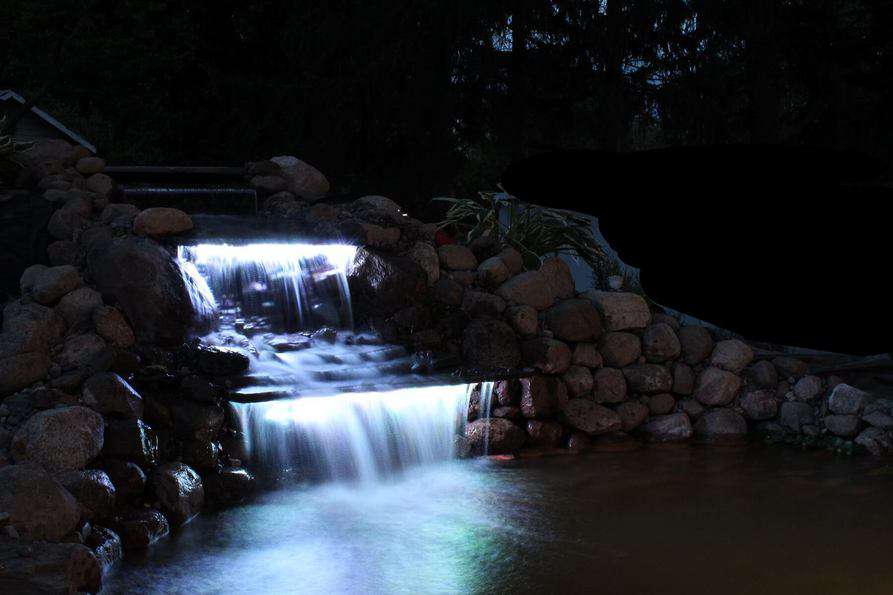 LED lighting under a backyard waterfall