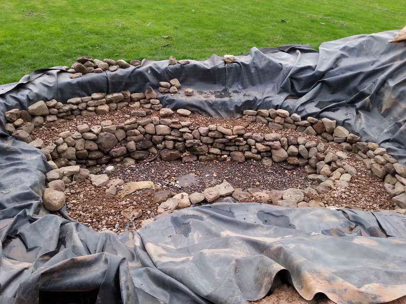 covering a pond liner with rocks