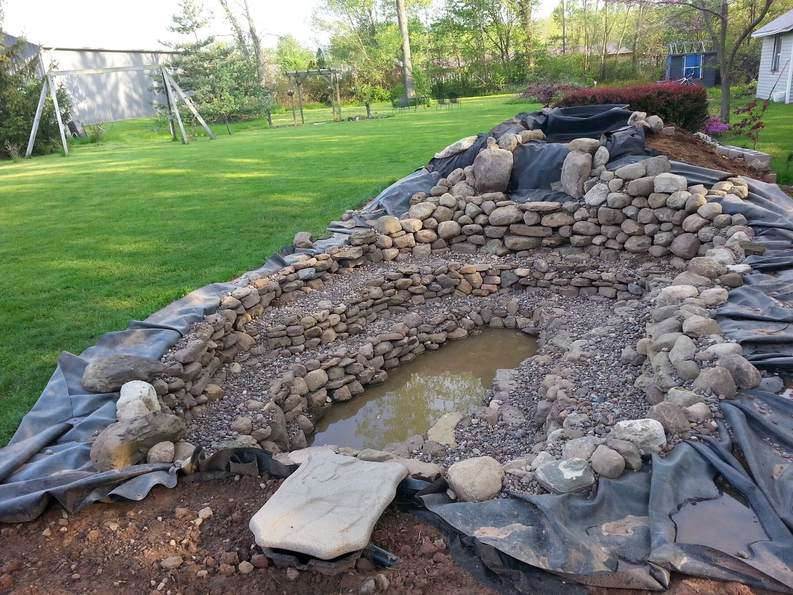 dry stacking stones over a pond liner